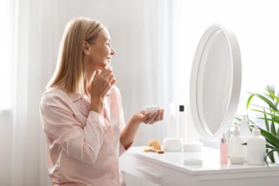 Skincare Concept. Attractive Middle Aged Lady Applying Moisturising Face Cream At Home
