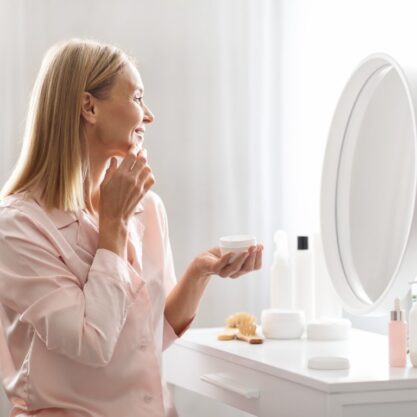 Skincare Concept. Attractive Middle Aged Lady Applying Moisturising Face Cream At Home